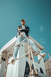 man standing at metal rail under blue sky thumbnail