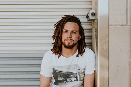 man in white crew-neck t-shirt beside gray roller shutter thumbnail