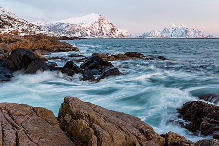 sea waves on rock cliff under gray sky thumbnail