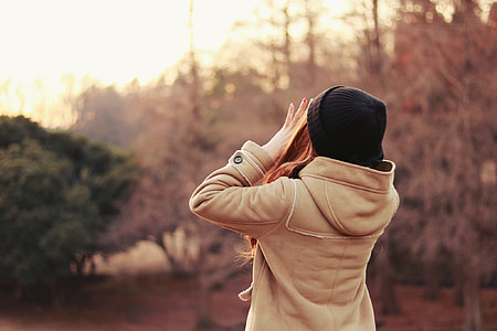 woman wearing brown jacket and black knit cap shouting near the trees during daytie thumbnail