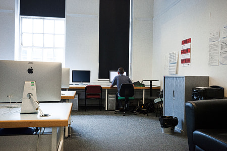 man wearing gray shirt sitting on green and black rolling chair using computer thumbnail