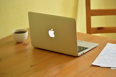 MacBook Air beside cup of coffee on brown wooden table thumbnail