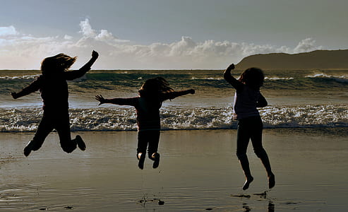 three children's jump shot on front of beach thumbnail
