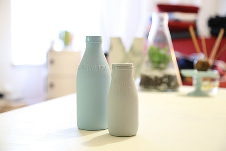 two gray and white glass bottles on white wooden table thumbnail