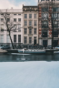 blue boat on body of water near concrete buildings thumbnail