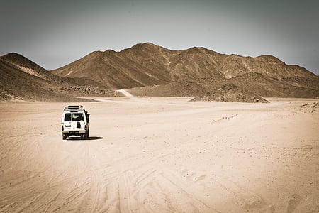 white SUV on the desert in a distance of a mountain thumbnail