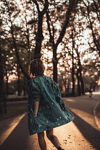 woman in blue denim jacket walking on road thumbnail