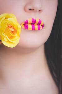 Woman Wearing Yellow and Pink Striped Lipstick Holding Yellow Rose thumbnail