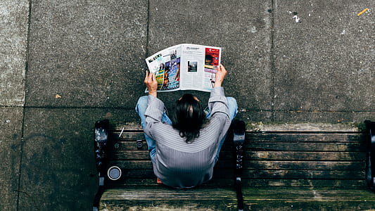 man in gray dress shirt sitting on while reading newspaper thumbnail