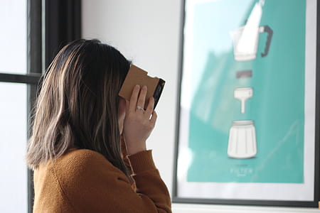 woman in brown sweatshirt near poster with black frame on wall thumbnail