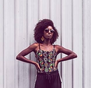 woman wearing green and black spaghetti strap top standing in front of wall thumbnail