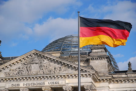 black, red, and yellow flag in pole beside concrete building thumbnail