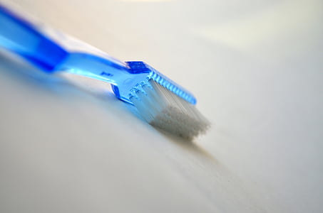 blue plastic white bristle toothbrush on white surface thumbnail