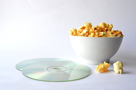 popcorns in bowl beside compact discs thumbnail