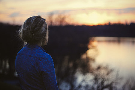 girl in blue chambray dress shirt facing on lake during golden hour thumbnail