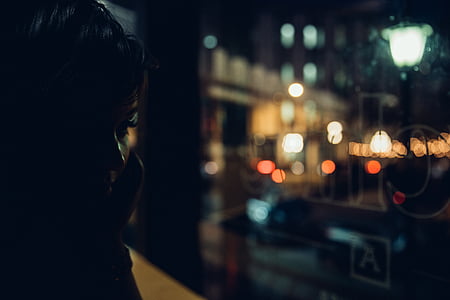 woman near the glass window during nighttime thumbnail