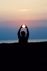 forced perspective photography of silhouette of person raising hands holding the sun during golden hour thumbnail