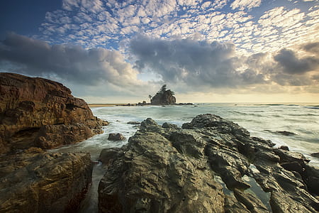 Brown Rocks on Seashore Under White Cloud Sky thumbnail