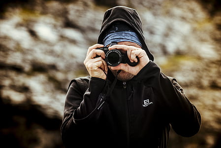 man wearing black zip-up jacket holding camera thumbnail