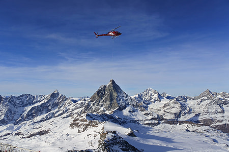 red helicopter above snow filled mountain thumbnail