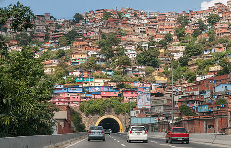 white car running on road towards tunnel near multicolored village thumbnail