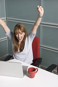 woman sitting on office chair front of laptop raising hands thumbnail