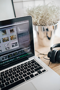 MacBook Pro with headphones on a wooden desk thumbnail