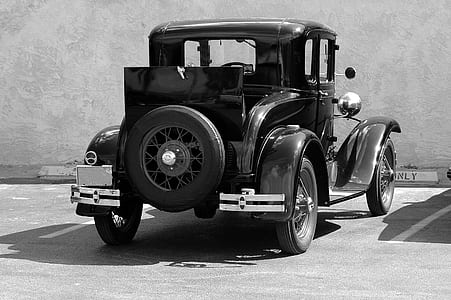 grayscale photography of vintage car parked near wall thumbnail