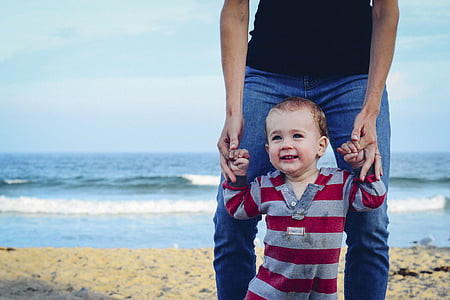man holding baby beside seashore thumbnail