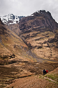 three people walking in hill pathway near snow mountain thumbnail