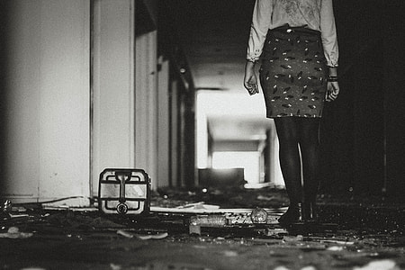 grayscale of woman standing inside building in hallway thumbnail