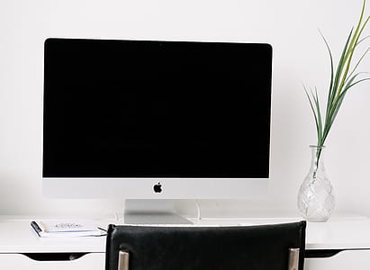 iMac on white wooden table near glass vase thumbnail