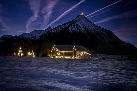 house with string lights with snow covered mountain background thumbnail