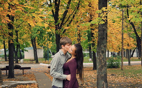 man kissing woman under maple trees thumbnail