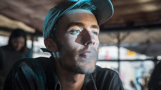 man wearing gray fitted cap and black collared top thumbnail