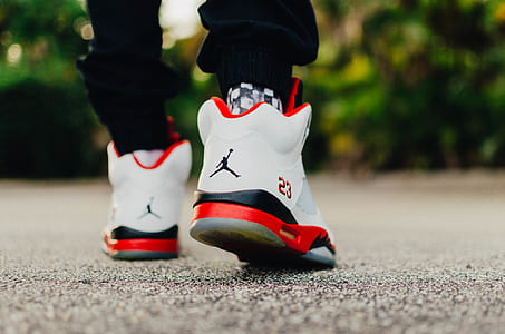 person wearing pair of white-and-red Air Jordan basketball shoes thumbnail