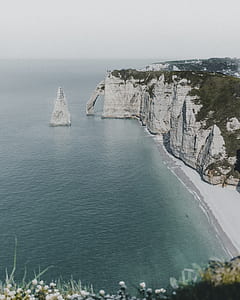 white and green cliff near seashore thumbnail