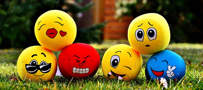 tilt-shift lens photography of six emoji balls on grass thumbnail