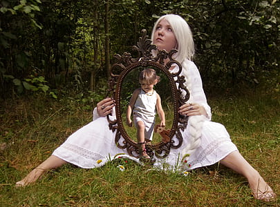 woman in white dress sitting on grass holding mirror thumbnail