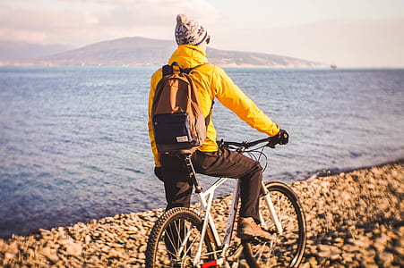 man riding hardtail bike besides body of water during daytime thumbnail