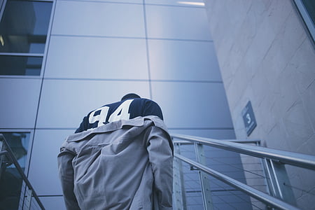 man taking off gray jacket standing on stair inside the building thumbnail