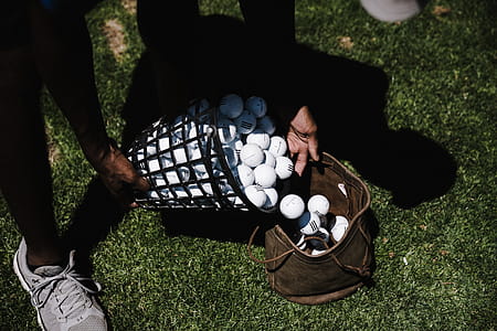 Person Pouring Golf Balls in Brown Leather Bag thumbnail