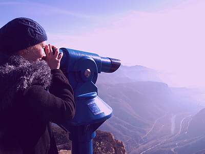 woman looking at the hills through scope during daytime thumbnail
