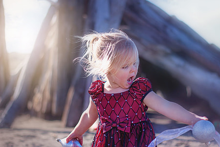 girl wearing red short-sleeved dress playing during day time thumbnail