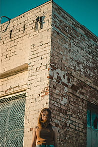 woman standing corner of brown brick house thumbnail