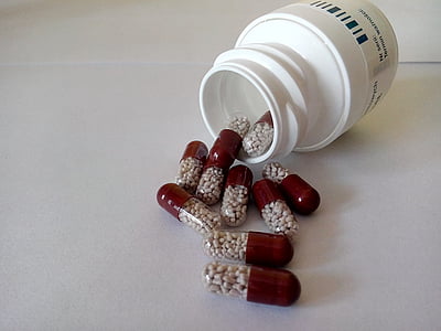 red-and-clear medicine capsules on white surface thumbnail