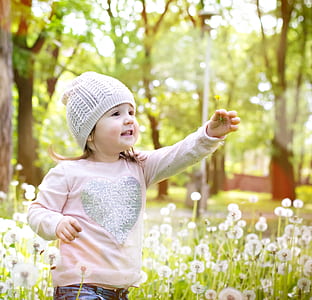 girl in pink shirt and gray knit hat near white flower plant thumbnail