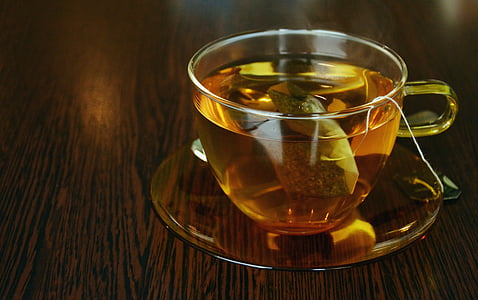 beige glass tea cup and saucer on top of brown wooden surface thumbnail