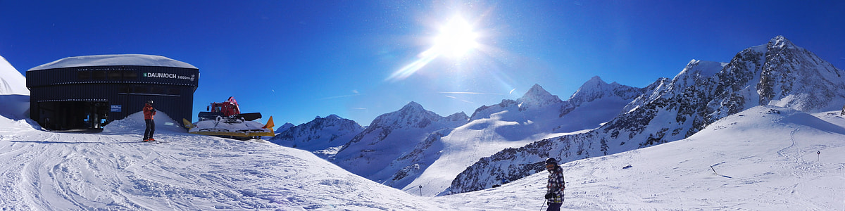panoramic photography of man standing on snow-covered mountain thumbnail