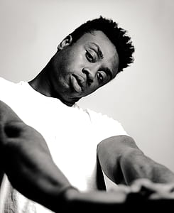 grayscale photo of man wearing crew-neck shirt stretching his arm thumbnail